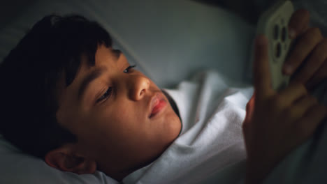 Un-Joven-Cansado-En-El-Dormitorio-De-Su-Casa-Acostado-En-La-Cama-Usando-Un-Teléfono-Móvil-Para-Enviar-Mensajes-De-Texto-Por-La-Noche-2